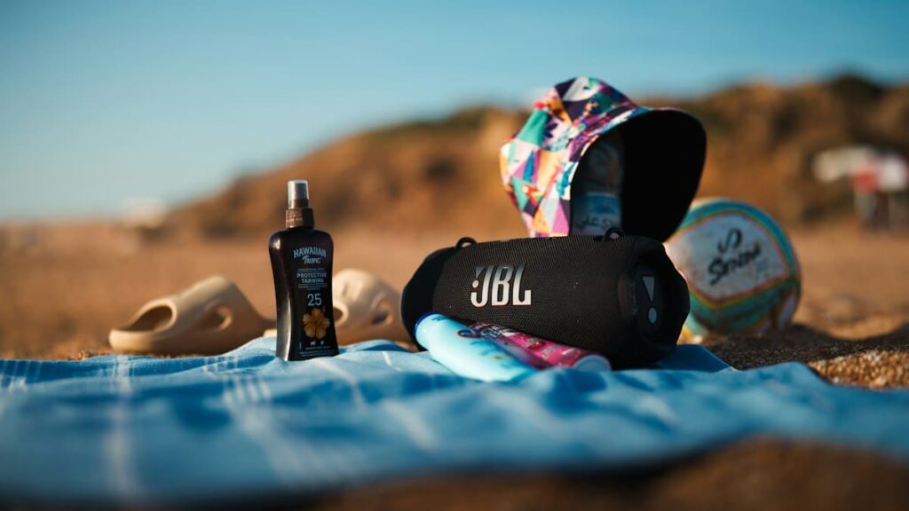 Beach essentials including sunscreen, sandals, a towel and a hat