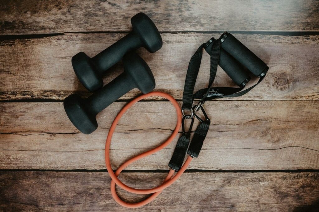 Two dumbbells and a resistance band on a wooden surface