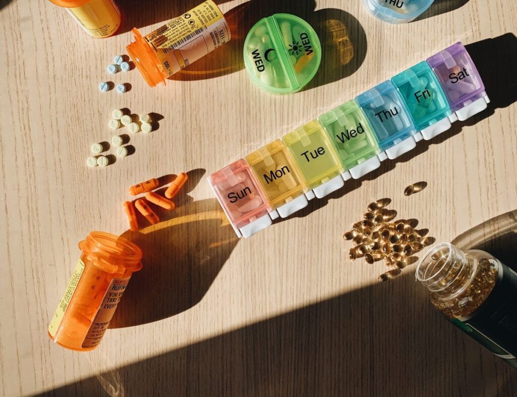 Pill organiser with medicine bottles and tablets on a wooden surface