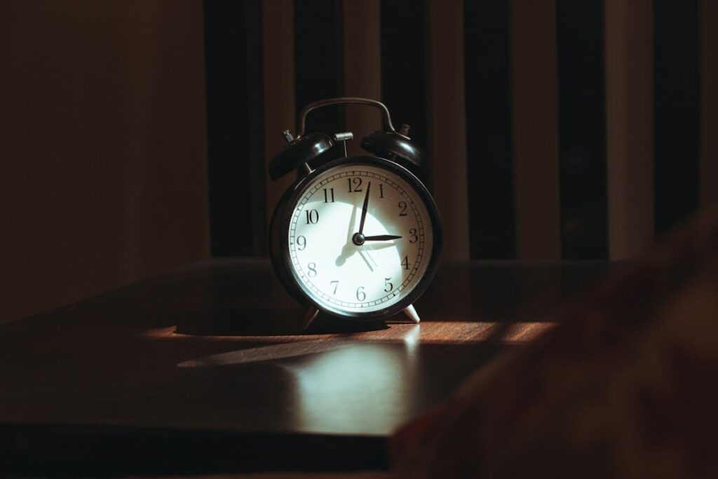 Alarm clock on a wooden bedside table at night