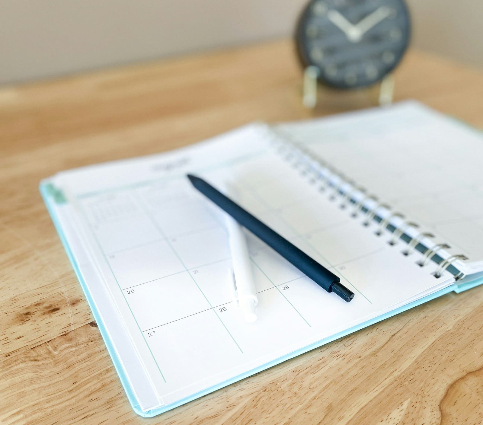 Open planner and a pen on a wooden desk, ready to mark the days