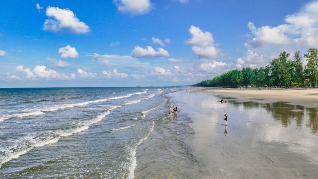 Quiet beach with waves and trees under a blue sky