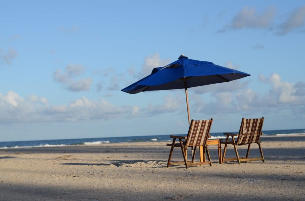 Empty beach chairs and an umbrella under a clear blue sky