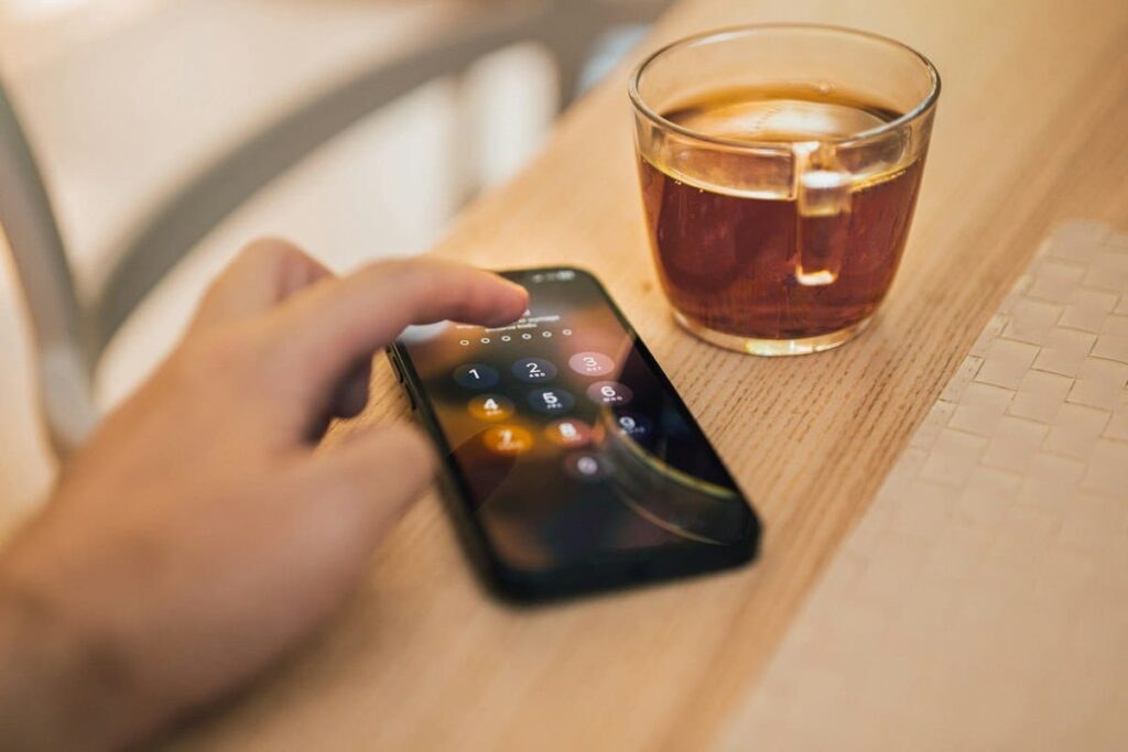 Hand holding a phone next to a cup of coffee