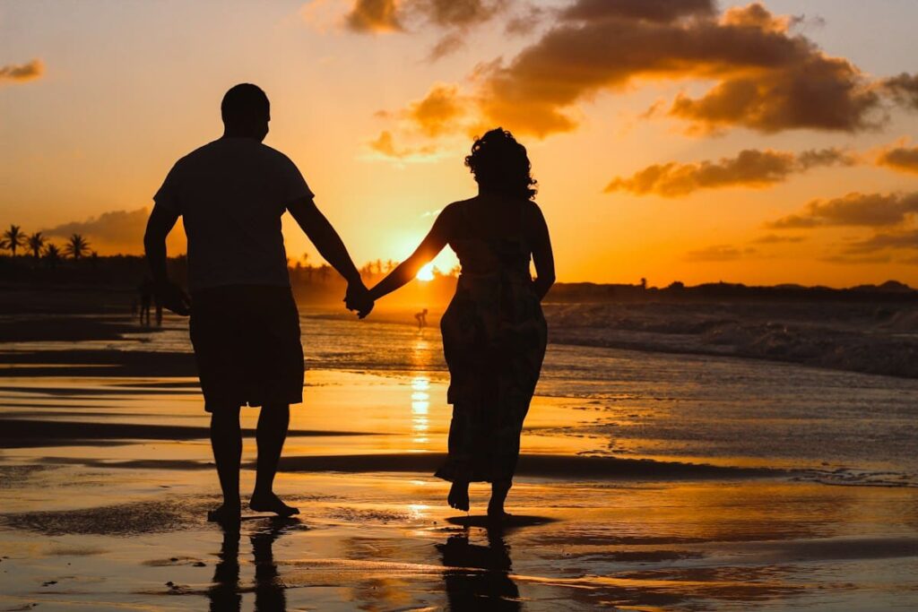 Couple standing at the water's edge at golden hour