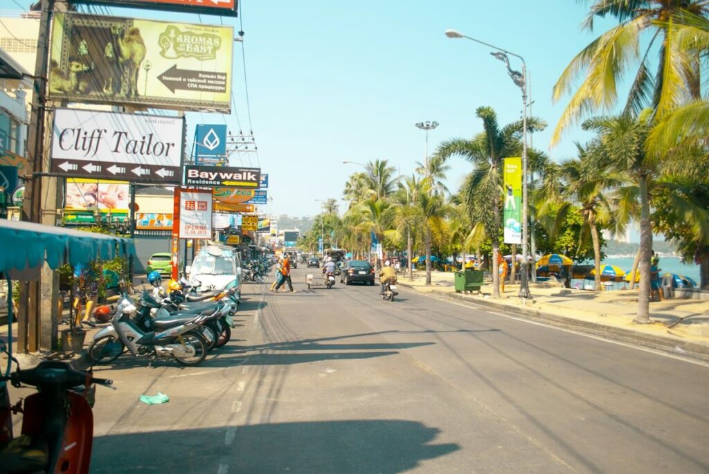 Sunny beach road lined with palm trees and shop signs