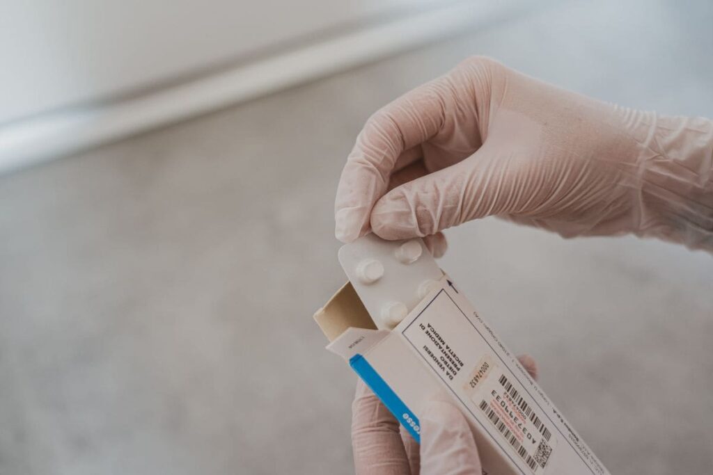 Gloved hands opening a box of medicine