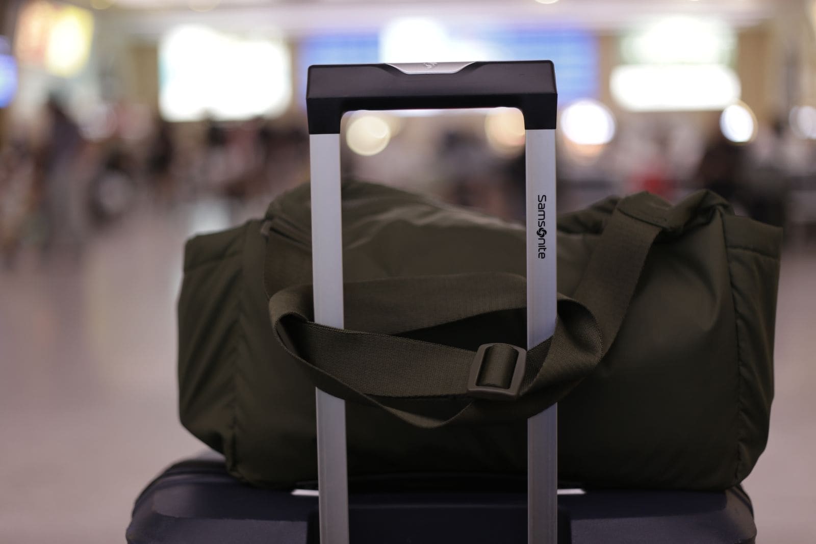 Suitcase with a duffel bag on top in a busy airport