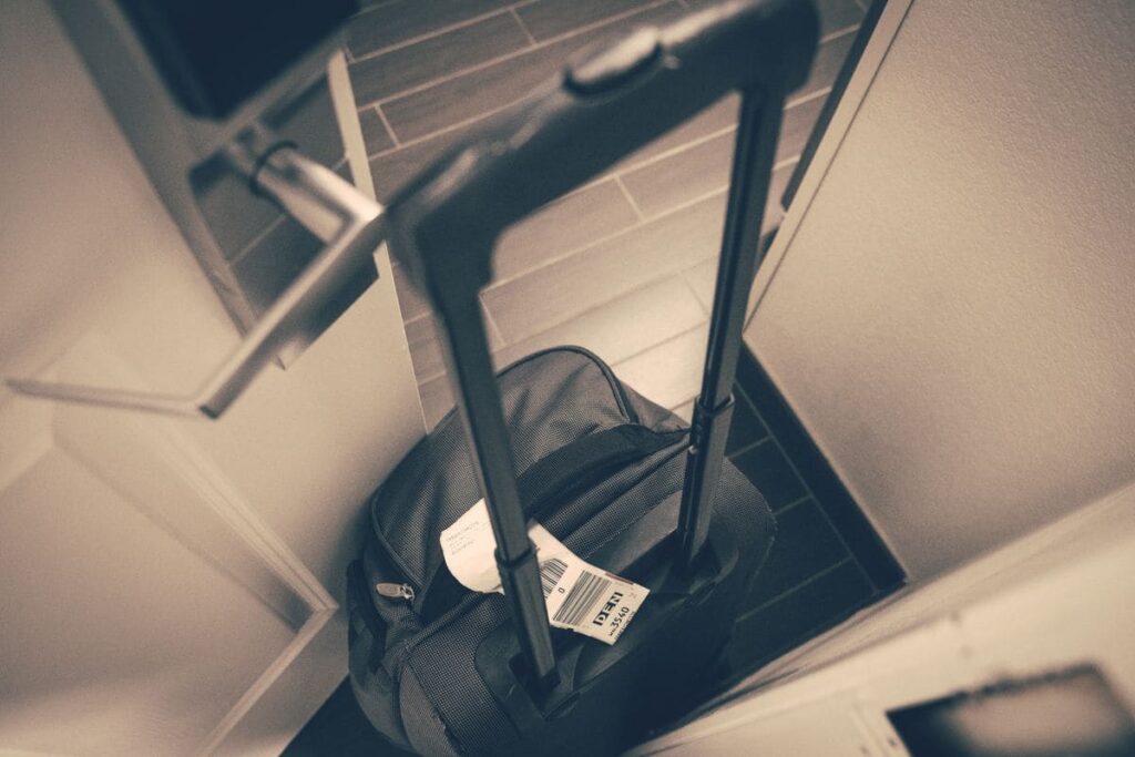 Travel suitcase with a luggage tag by a hotel room door