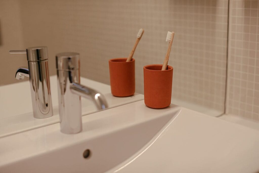 Bathroom sink with toothbrushes standing in red cups