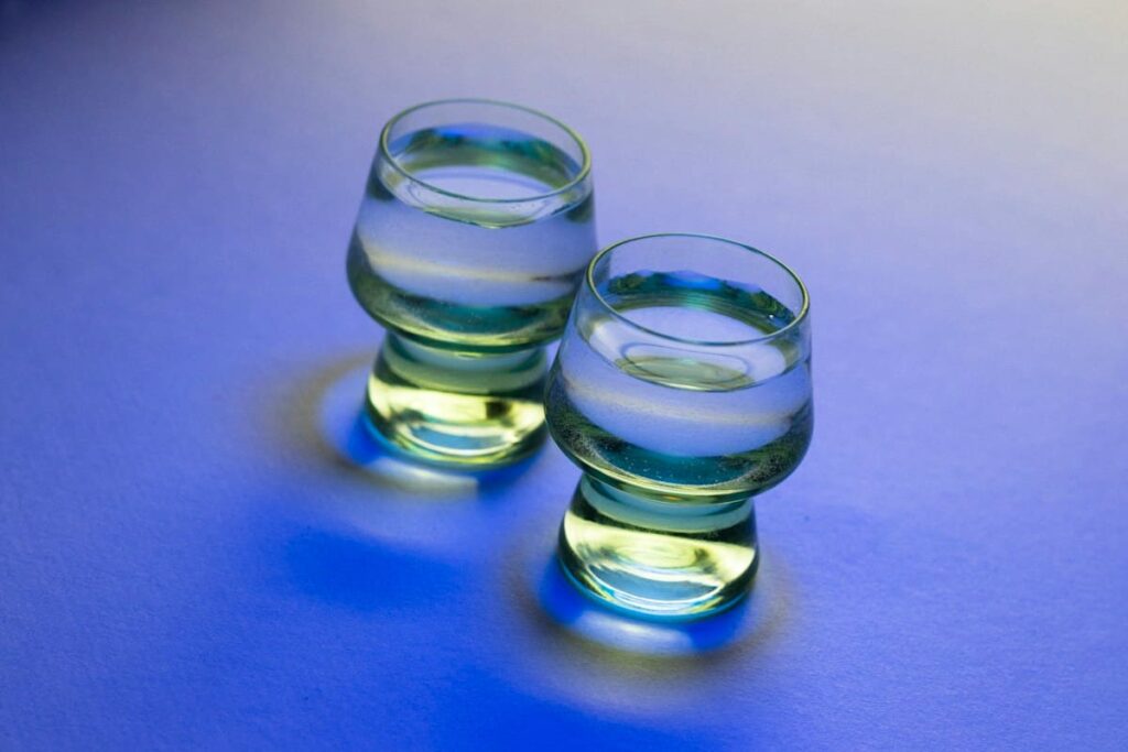 Two glasses of clear water side by side on a blue surface