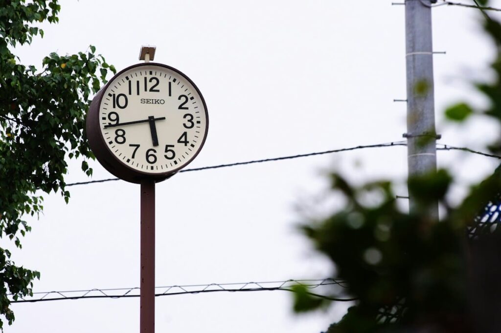 Round outdoor clock on a pole against a pale sky